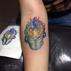 a tattoo on the leg of a person with a blue and yellow mask in the background