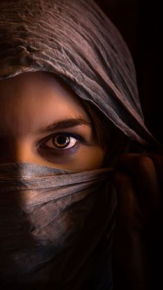 a woman's face is covered with a veil and eyes are wide open to the camera