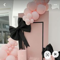 balloons and candles are on display in front of a pink wall with black bow decorations