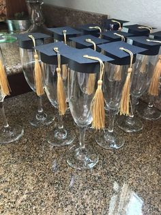 several wine glasses with graduation caps and tassels are lined up on the counter