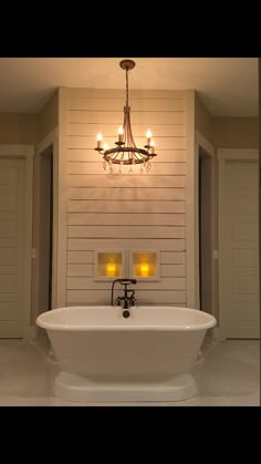 a white bath tub sitting under a chandelier