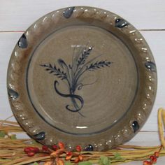 a ceramic plate sitting on top of a table next to some dried grass and flowers