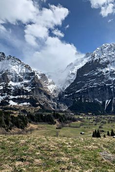 the mountains are covered in snow and green grass