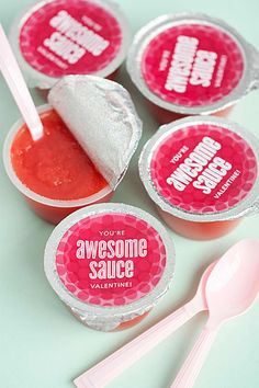 four pink and white cupcakes with spoon next to them on a blue surface