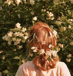 a woman with red hair and white flowers in her hair is looking into the distance