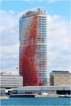 a tall building with red and blue paint on it's side next to the water