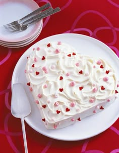 a heart shaped cake sitting on top of a white plate next to a knife and fork