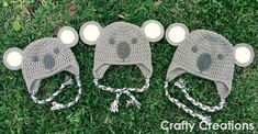 three crocheted hats are laying on the grass with two ears attached to them