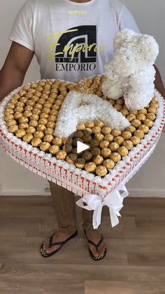 a man holding a large heart shaped box filled with cookies and teddy bears in it