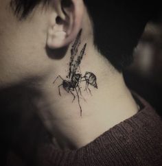 a close up of a person's neck with a spider tattoo on the side