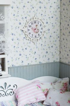 there is a clock on the wall above the bed in this room with floral wallpaper