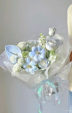 a woman holding a bouquet of white and blue flowers