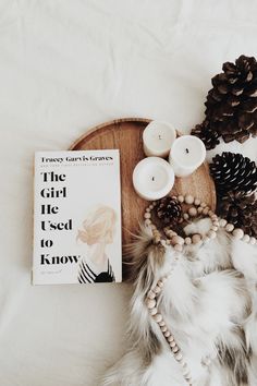 the girl i used to know is next to some pine cones, candles and a book