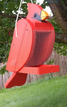 a red bird feeder hanging from a tree