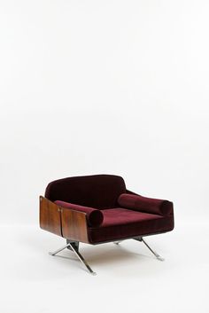 a red chair sitting on top of a white floor next to a wooden frame and metal legs