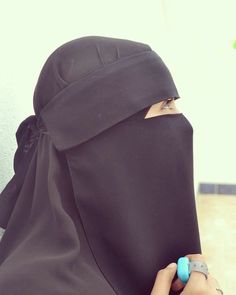 a woman wearing a black hijab with a ring on her finger