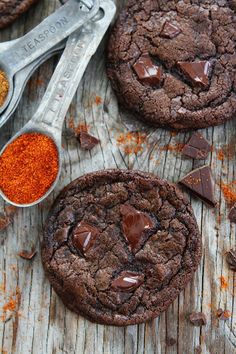 chocolate cookies with sea salt and spoons on wooden table next to them, one has been cut in half