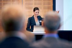 a woman giving a presentation in front of an audience at a business meeting stock photo