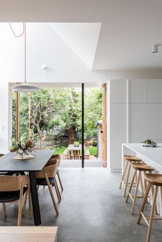 an open kitchen and dining room area with wooden tables, chairs, and sliding glass doors