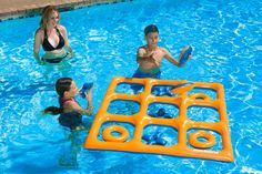 two children and an adult are playing in the swimming pool with frisbees