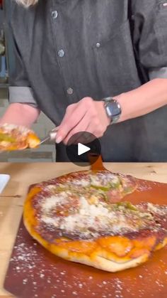 a woman cutting pizza on top of a wooden table