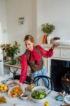 a woman standing in front of a table filled with plates and bowls full of food