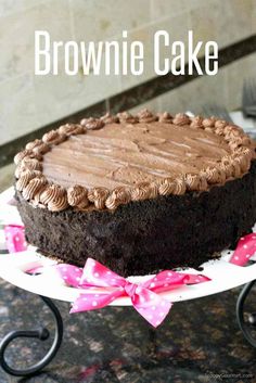 a chocolate cake sitting on top of a white plate with pink ribbon around the edges