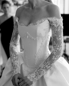 black and white photo of woman in wedding dress with long sleeves on her shoulder, looking off to the side