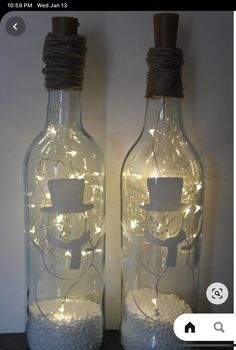 two glass bottles with lights in them on a table