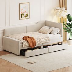 a day bed with drawers underneath it in a room next to a potted plant