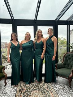 three women in green dresses standing next to each other on a rug and looking at the camera