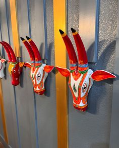 three red and white cow head mounted to the side of a wall with long horns