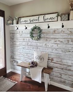 a white bench sitting in front of a wooden wall with two wreaths on it