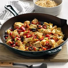 a pan filled with food on top of a wooden cutting board