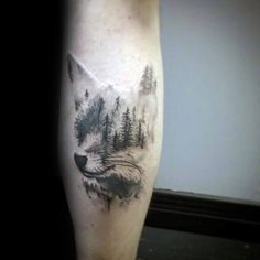 a man's leg with a tattoo of a wolf and trees in the background