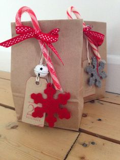 two brown bags with red and white ribbons tied to them, one has a snowflake ornament hanging from it