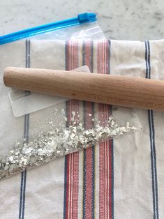 a wooden baseball bat sitting on top of a striped cloth next to a plastic bag