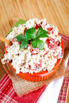 a red bowl filled with rice and garnished with fresh mint leaves on top