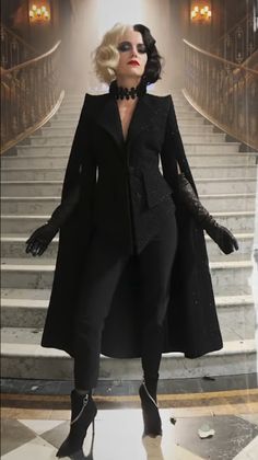 a woman dressed in black is standing on some stairs with her hands out to the side