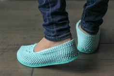 the feet of a person wearing blue crocheted slippers