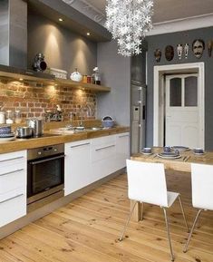 a kitchen with wooden floors and white cabinets is pictured in this image, there are two chairs at the table