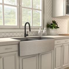 a kitchen with white cabinets and countertops has a large window that looks out onto the trees outside