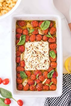 a square casserole dish filled with tomatoes, basil and mozzarella