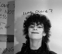 a woman with curly hair standing in front of a whiteboard that has writing on it