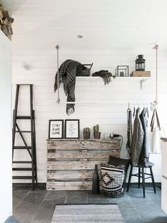 a room with white walls and wooden shelves on the wall, some clothes hanging up