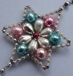 a silver and pink necklace with bells hanging from it's center, on a white surface