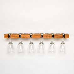 six wine glasses are lined up in a row on a rack with wooden bar ends