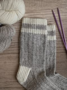 two skeins of yarn next to a pair of socks and crochet hooks