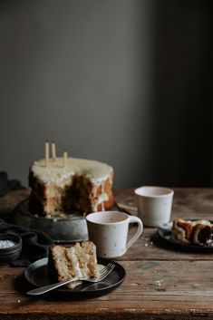 there is a piece of cake on the table with cups and saucers next to it