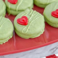 green cookies with red heart decorations on a red plate, ready to be eaten for valentine's day